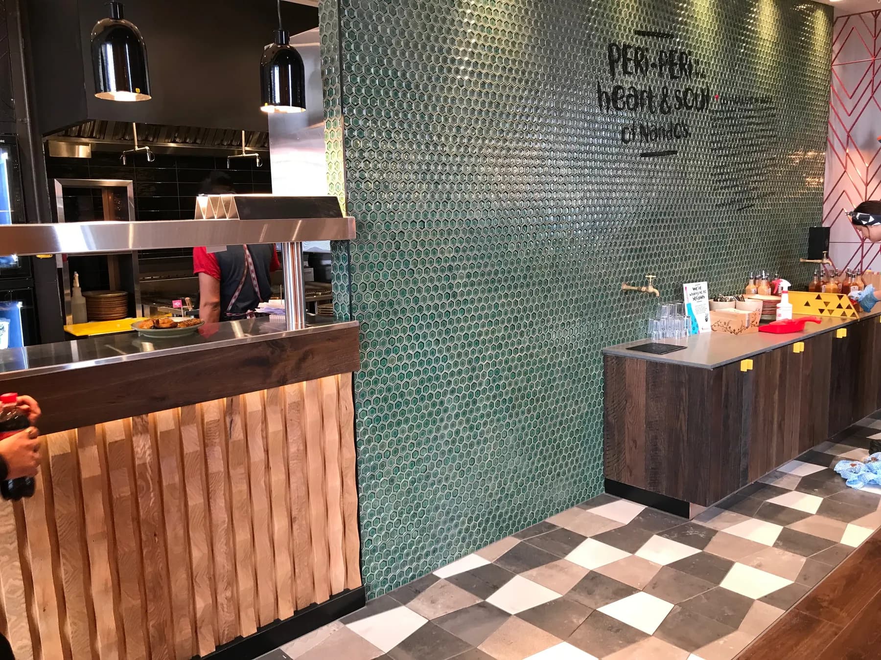 Nando’s Northlands counter — green penny-round feature wall and checkerboard floor tiling, Christchurch